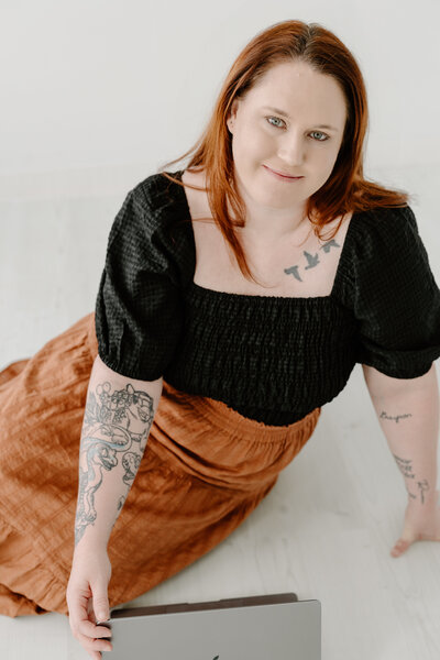Bethany Simms smiling up at camera wearing a black shirt and orange skirt