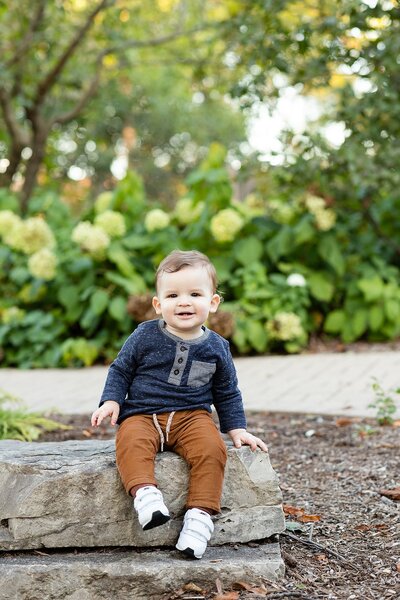 Toddler boy sitting on rock smiling