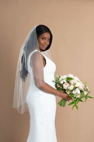 Bride wearing a simple classic bridal veil and holding a white and pink bouquet