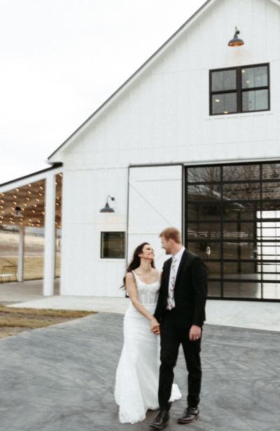 Couple standing outside big white barn