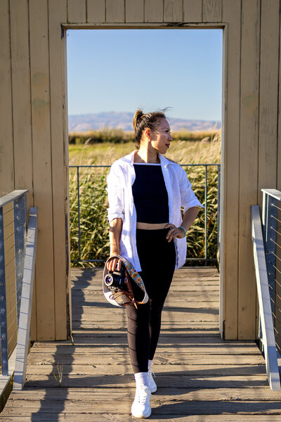Bay Area Lifestyle Photographer - Ellobelle Photography Family Photographer walks through wooden structure surrounded by tall grass and sunset light
