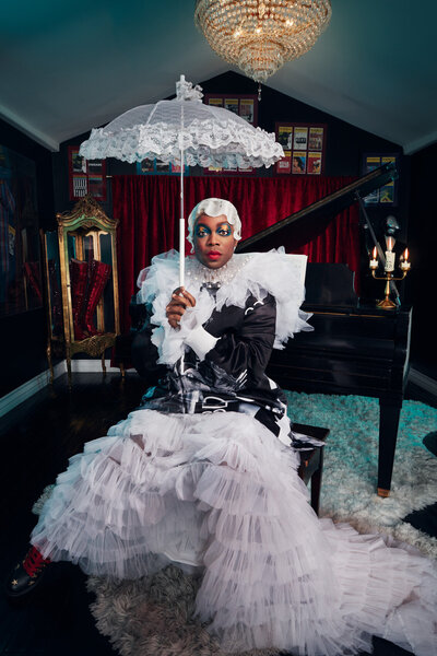 Artistic portrait of Todrick Hall in an elaborate outfit, striking a playful pose, shot by Ylva Erevall.