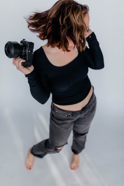 Woman poses for the camera with Nikon Z6II Camera held against her cheek.