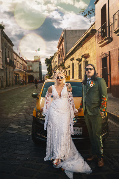 couple standing in front of a car on wedding day together