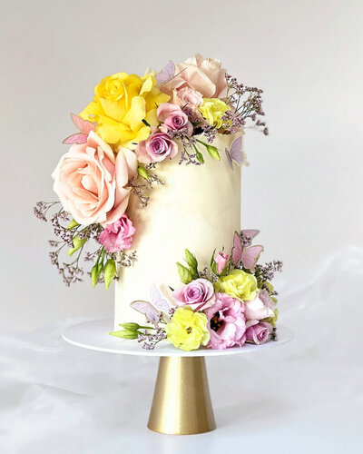 Single tier cake with bright colourful spring florals with roses and butterflies