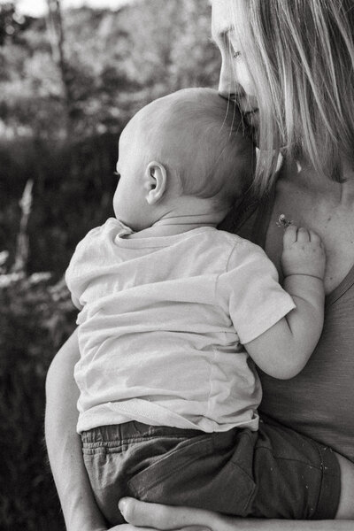Mother holding baby as baby clutches clover flower