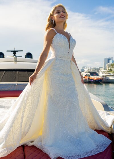 Model wearing pearl wedding dress on yacht red couch