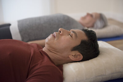 Man laying down in a yoga session with eyes closed