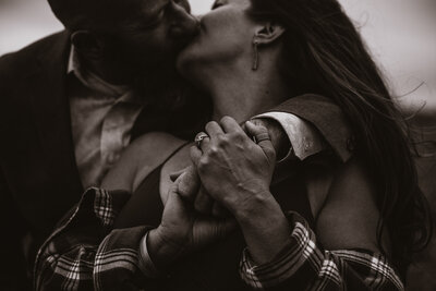 couple holds hands and shares intimate kiss