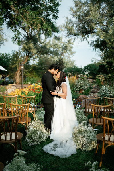 Bride and groom stand with foreheads together in front of a lake