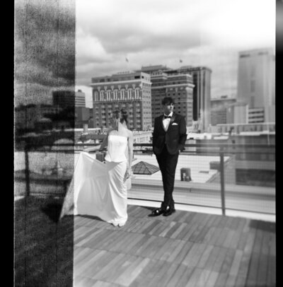 Bride and groom on a rooftop with a city skyline behind them, captured on film by a Washington wedding photographer.
