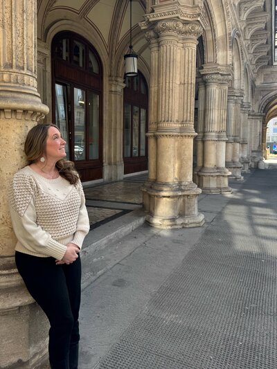 Terra from Adventures by Terra looking at architecture in Vienna, Austria wearing an ivory sweater and black pants