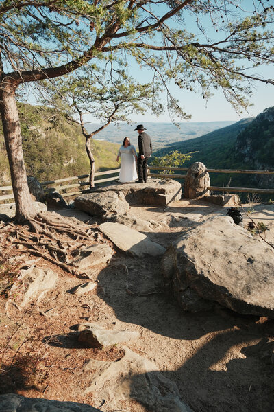 Couple holding hands on rocks in wedding attire