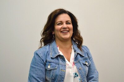 A portrait of Amy Hasemann, a stylist at 212 Salon, Spa, & Barbershop, wearing a denim jacket and smiling at the camera.