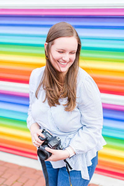 Photographer poses in front of rainbow wall during brand session photographed by Baltimore Branding Photographer