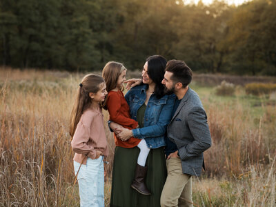 family photo of parents and two daughters on a fall day in the park