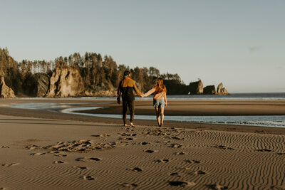 Hannah and Adam walking hand in hand on the beach