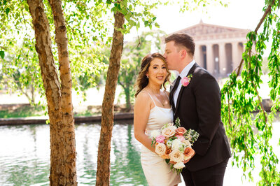 Groom kissing bride forehead after elopement outside of Parthenon in Nashville