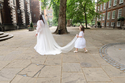 Bride and bridesmaid walking through courtyard of Temple Church, London 