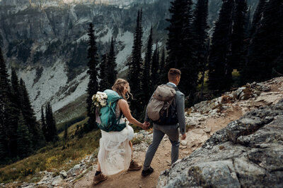 couple in wedding attire hiking to Washington elopement location