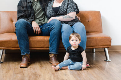 Baby girl sitting on the floor in front of her parents