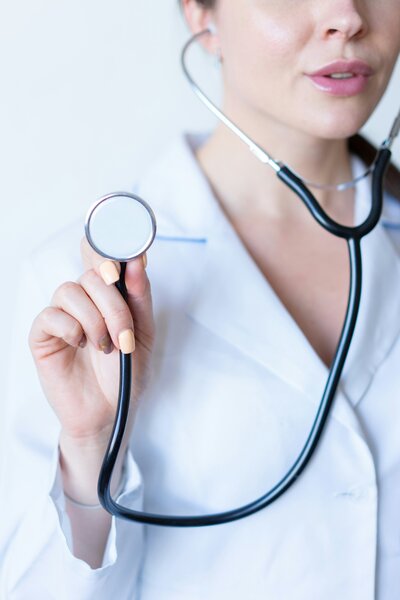 Stock photo of a woman in a white lab coat holding a stethoscope, representing reviewing treatment options for hormone therapy at Wellness & Hormone Health in Centennial, Colorado.