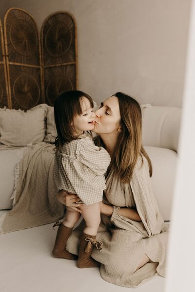 Sweet family portrait captured by a Mullingar photographer, showing a mother embracing her toddler with a kiss