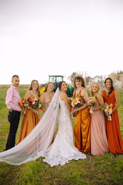 Bride and bridesmaids in vibrant dresses holding bouquets in an open field