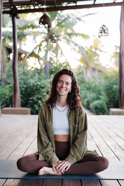 Brittany Ugolini, certified yoga and Pilates teacher, seated in a peaceful outdoor space in San Miguel de Allende, smiling warmly during a mindfulness practice.