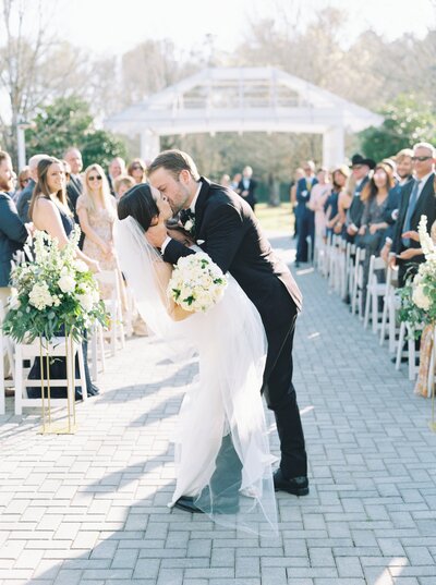 just married bride and groom kissing in the middle of the aisle at Fox Hall Resort in Douglasville, GA