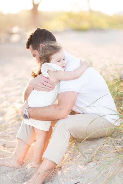 toddler daughter hugging father at a beach family session by Miami lifestyle photographers David and Meivys of MSP Photography