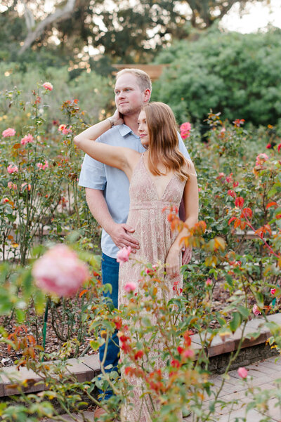 Couple posing for an image while standing in a rose garden at sunset during their couples portraits
