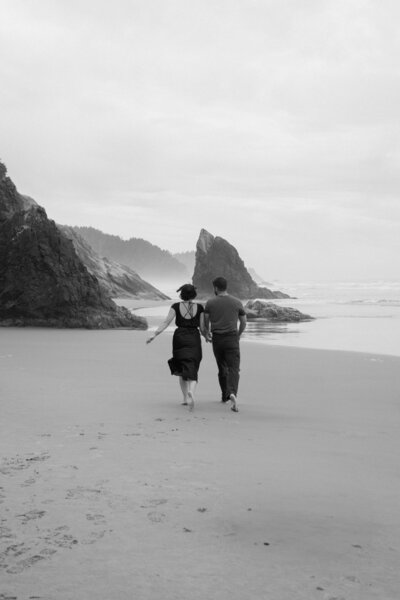 Cannon beach engagement session with the couple running on the beach.