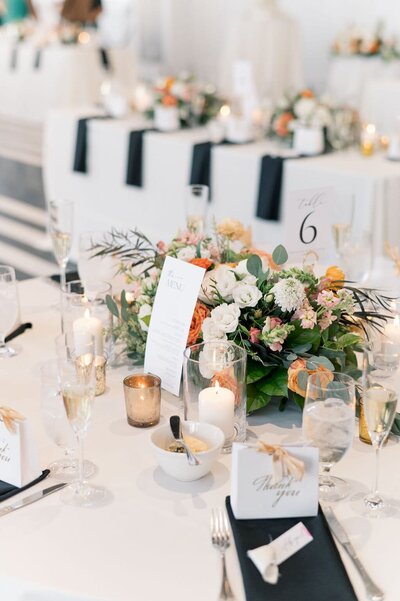 wedding reception table with white, orange, and yellow flowers