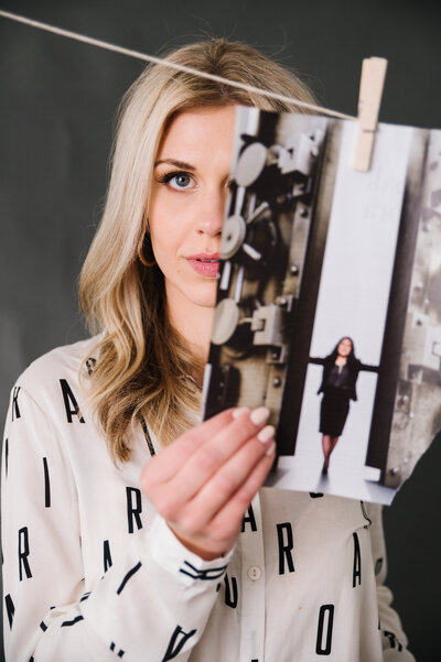 Sarah Klongerbo with her face partially covered by a printed image hanging by a clothespin on a string