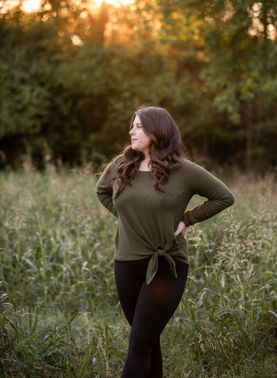 senior girl in field in golden sunset light
