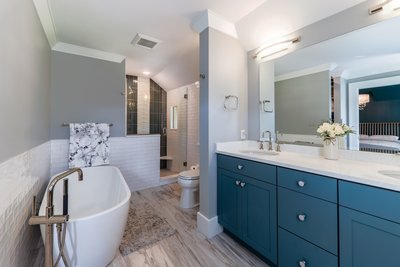 freestanding bathtub with blue cabinetry