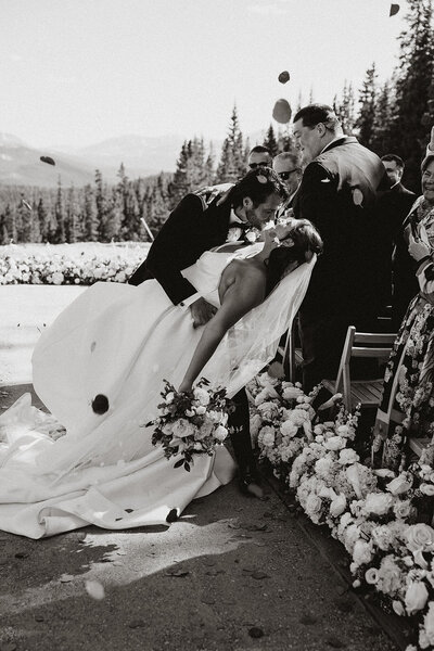 Bride and groom exit snowy winter ceremony at Breckenridge elopement with smiles and snow falling.