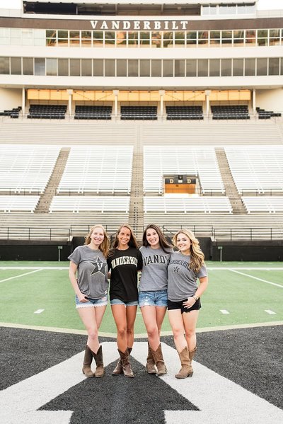 4 Senior girls in their Vanderbilt University shirts on the football field