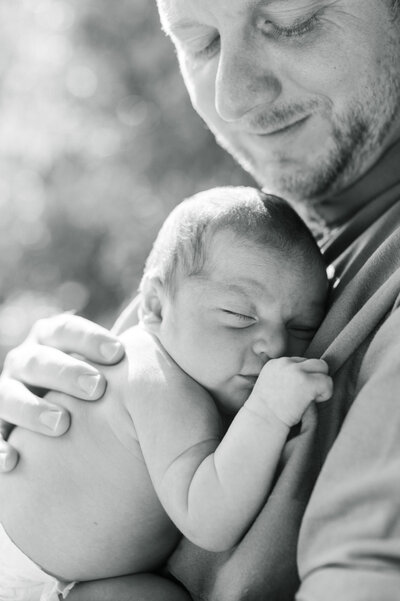 San Antonio newborn photographer captures a sweet moment as a new dad snuggles his sleeping baby.