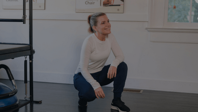 pilates instructor kneeling while teaching a class 