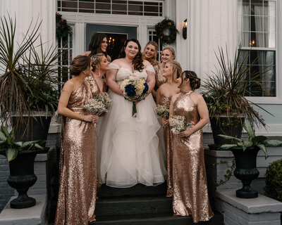 Bride stands with her bridesmaids on the stairs at Englund Estate Wedding Venue.