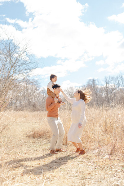 family of 3 playing in a field