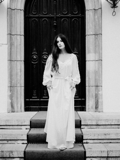 Romanian bride in a long sleeve wedding dress standing on steps in black and white