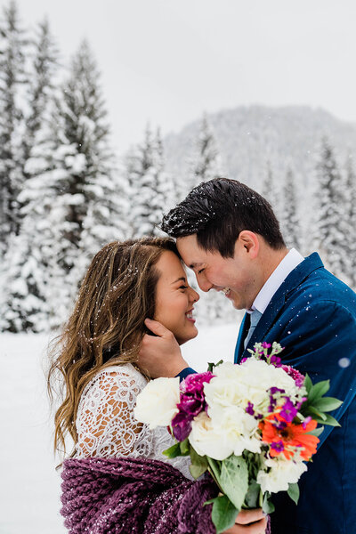 bride and groom embracing during snowy elopement ceremony
