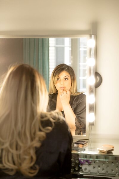 neelam kaur, ottawa makeup artist, looking in the mirror as she does her own makeup