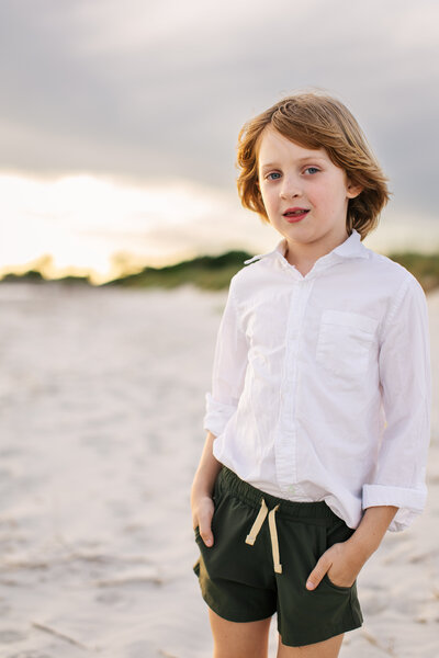 Boy with red hair and green shorts  staring at the camera on beach at Sullivan's Island
