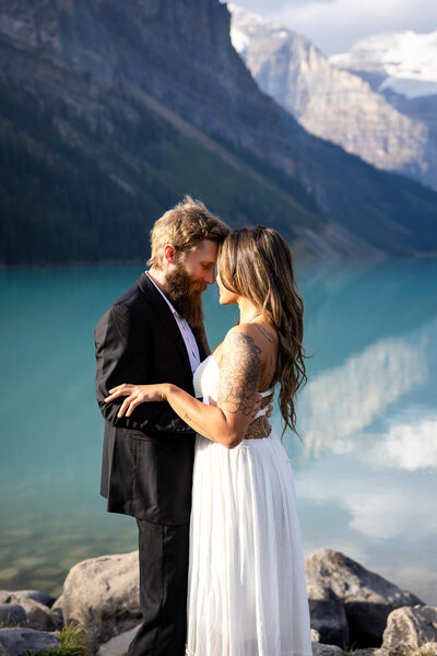 A couple embracing each other in front of the iconic lake louise view. 