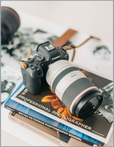 photo of a woman smiling at the camera while holding a camera in her right hand