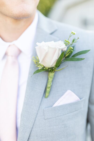 Groom wearing light grey suit with blush pink tie and pocket square and light grey suit.